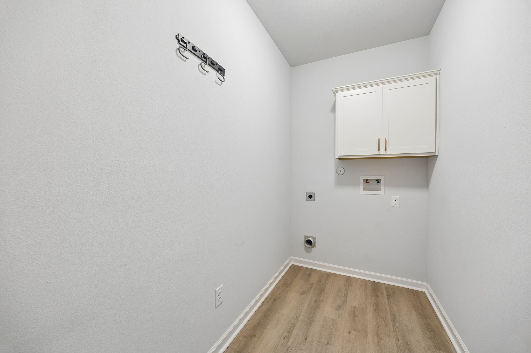 10902 Bonfire Trail Beasley, TX 77417 - Photo 24 of 36 This laundry room has light-color walls and vinyl plank flooring. It features upper storage cabinets and hookups for a full size washer and dryer.