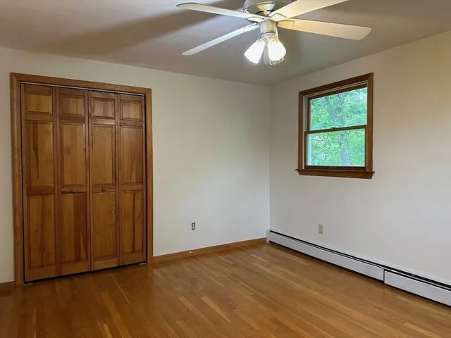 an empty room with wooden floor closet and windows