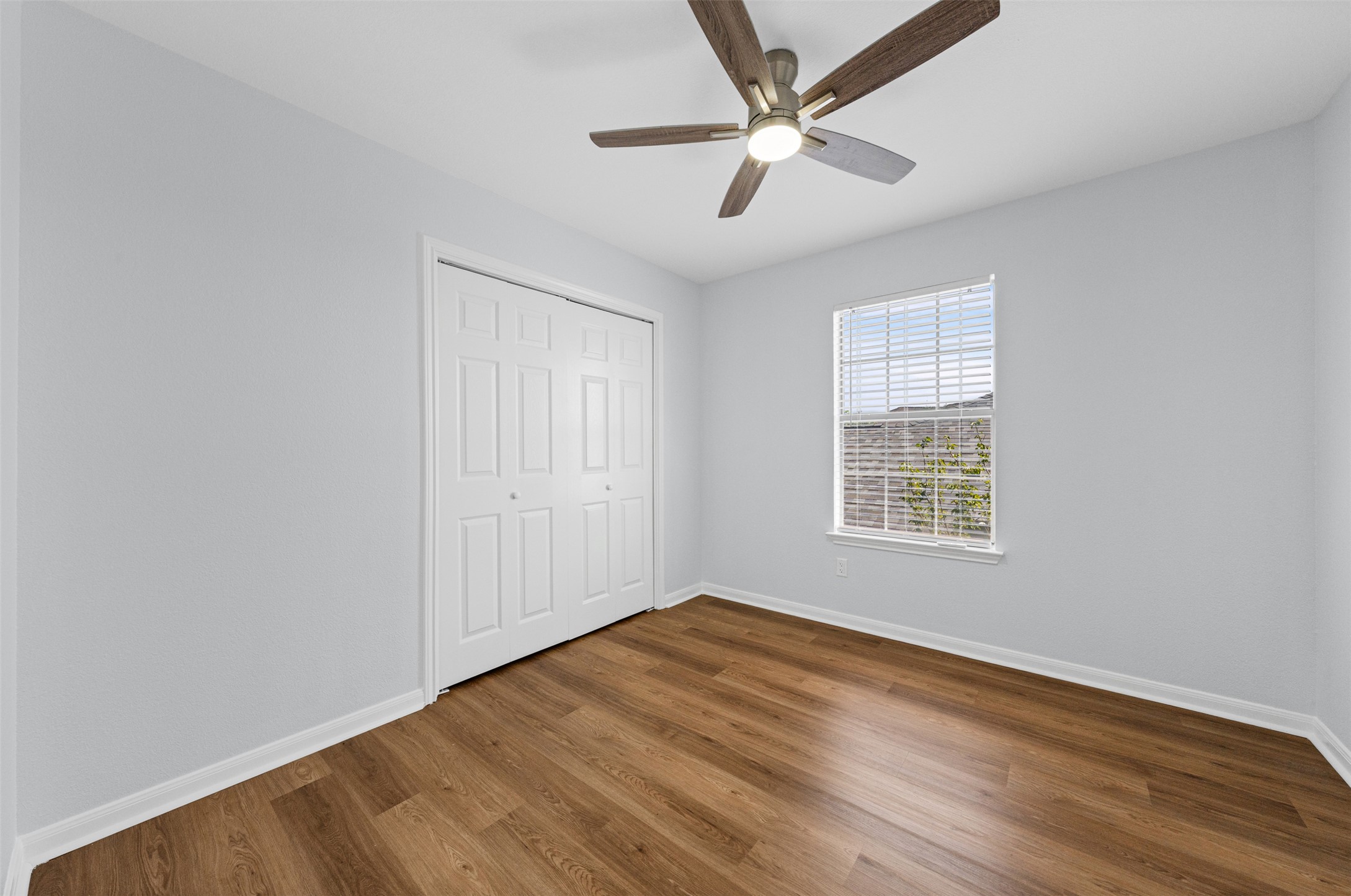 243 Engineers Pass Jarrell, TX 76537 - Photo 28 of 40 Bedroom featuring wood-finish flooring, light gray walls, a ceiling fan with integrated lighting, a window with blinds, and bi-fold closet doors