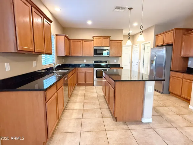 a large kitchen with stainless steel appliances granite countertop a stove a sink dishwasher and a refrigerator