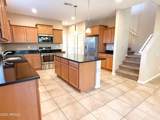 a kitchen with stainless steel appliances granite countertop a refrigerator and a stove top oven