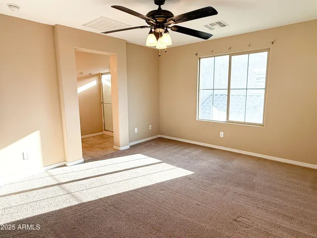 an empty room with chandelier fan and windows