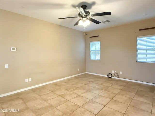an empty room with a chandelier fan and windows