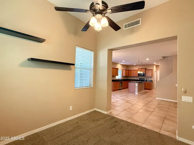 a view of a livingroom with a ceiling fan and a kitchen space