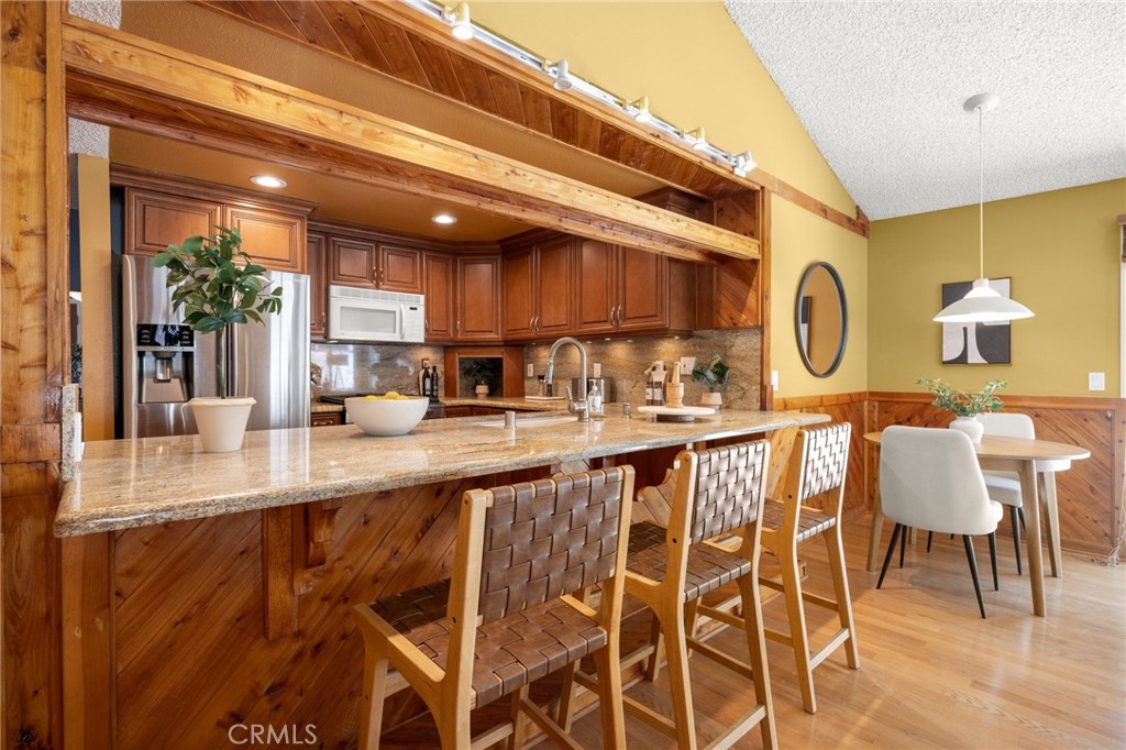 26017 Redbluff Drive Calabasas, CA 91302 - Photo 11 of 29 a kitchen with stainless steel appliances granite countertop a table chairs in it and wooden floors