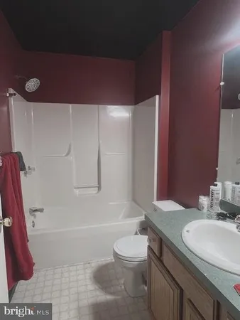 a bathroom with a granite countertop bathtub shower sink vanity and toilet