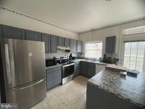 a kitchen with granite countertop a refrigerator stove top oven and sink