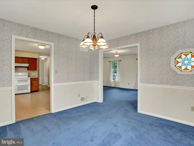 an empty room with kitchen and a chandelier fan