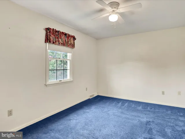 an empty room with ceiling fan and window