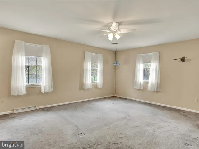 an empty room with chandelier fan and windows