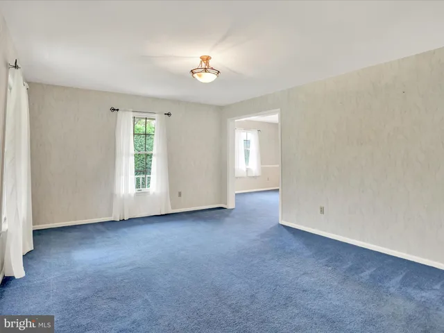 an empty room with windows and chandelier fan