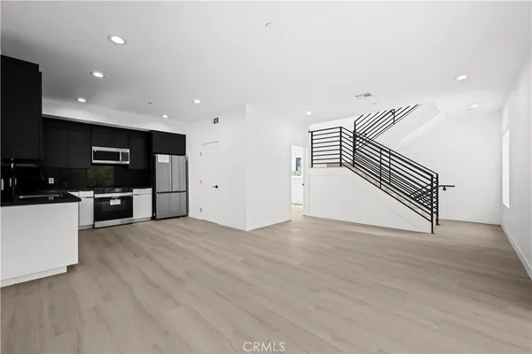 a view of kitchen with stainless steel appliances kitchen island wooden floor and window