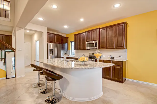 a kitchen with kitchen island granite countertop a sink appliances cabinets and furniture