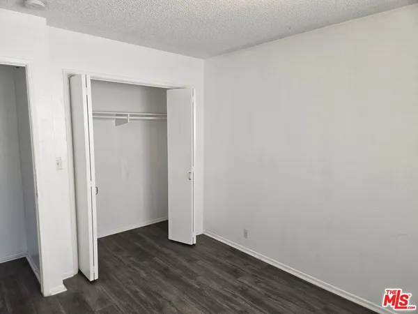 a view of an empty room with wooden floor & closet
