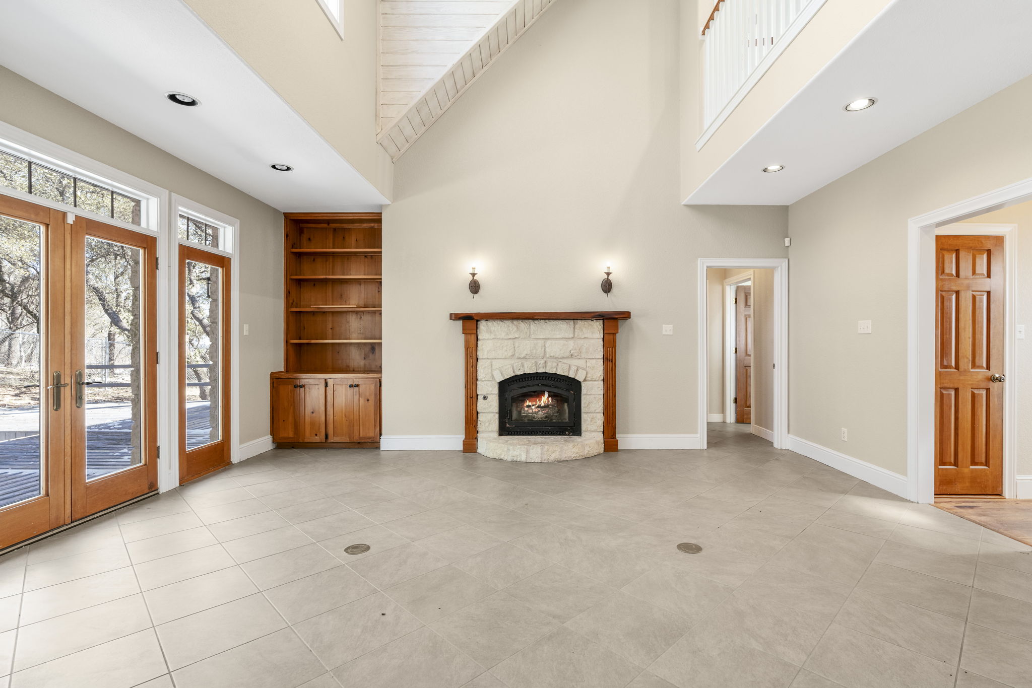 310 County Road 317 Georgetown, TX 78626 - Photo 12 of 40 Unfurnished living room featuring french doors, a towering ceiling, built in shelves, recessed lighting, and a fireplace