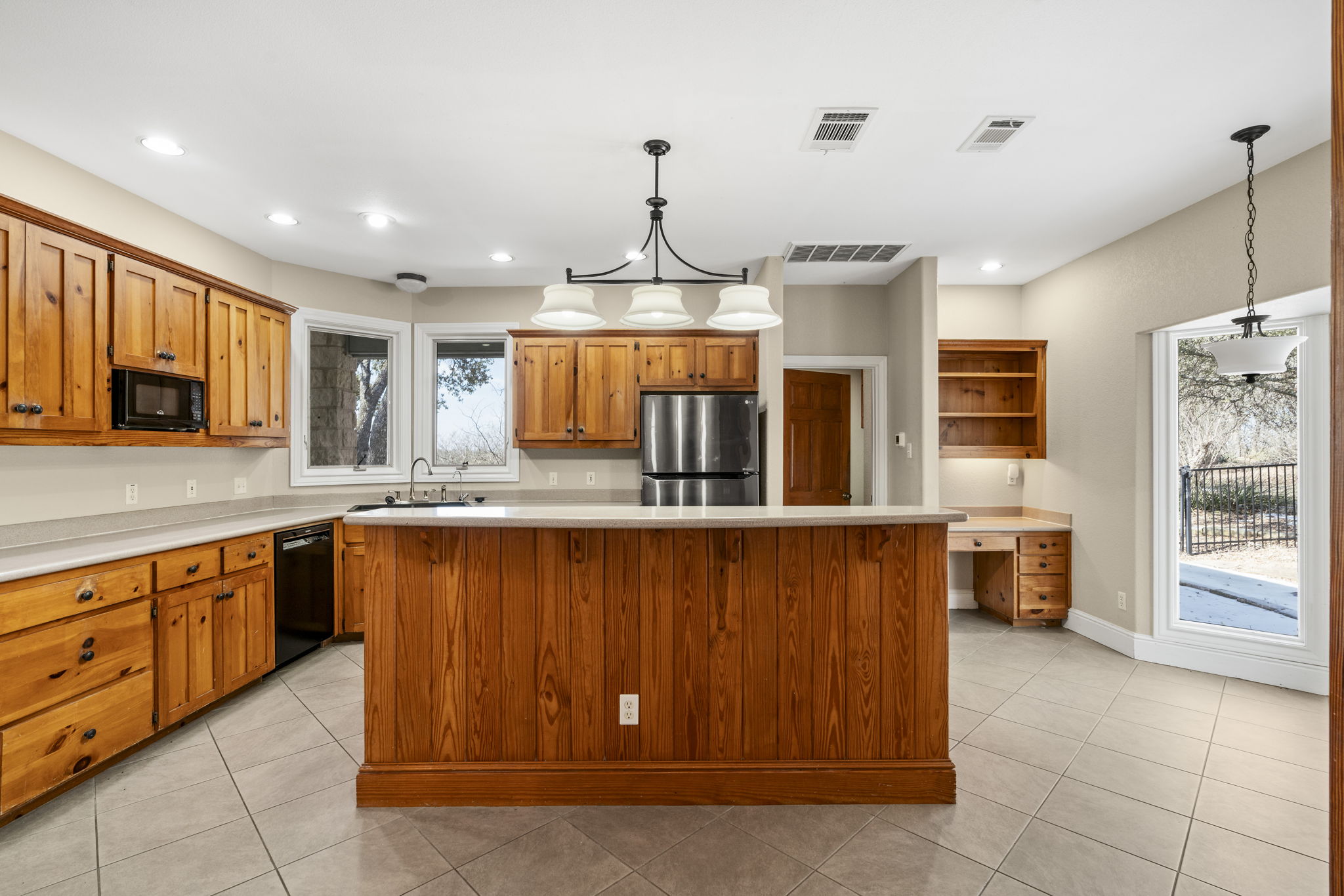 310 County Road 317 Georgetown, TX 78626 - Photo 6 of 40 Kitchen featuring light countertops, brown cabinetry, light tile patterned floors, black appliances, and recessed lighting