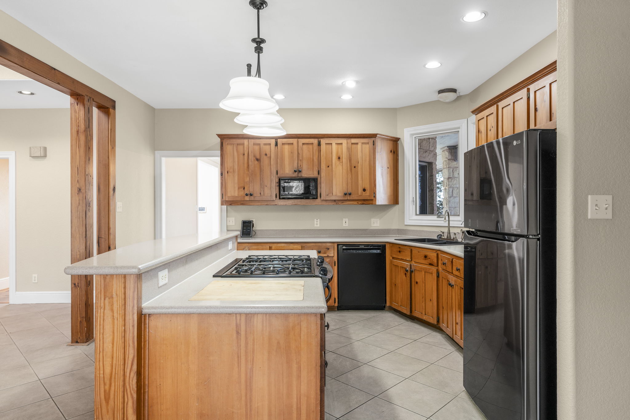 310 County Road 317 Georgetown, TX 78626 - Photo 9 of 40 Kitchen with black appliances, decorative light fixtures, light tile patterned flooring, light countertops, and a center island