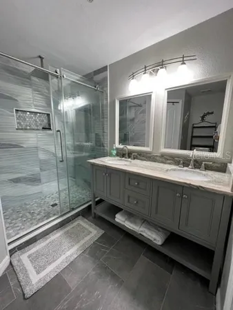 a bathroom with a double vanity sink mirror and shower