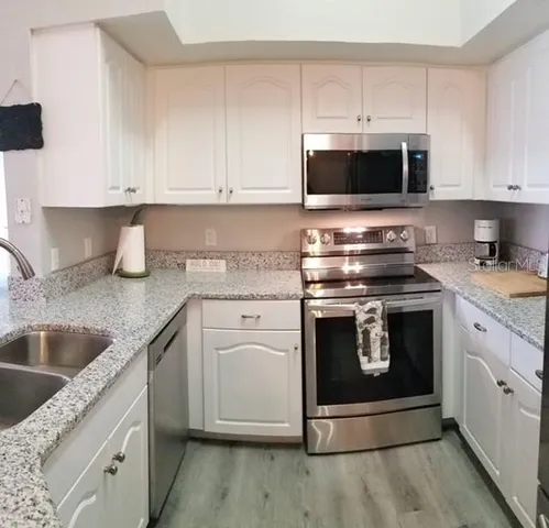 a kitchen with stainless steel appliances granite countertop a stove microwave and sink
