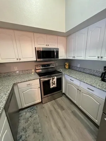a kitchen with granite countertop a stove top oven and cabinets