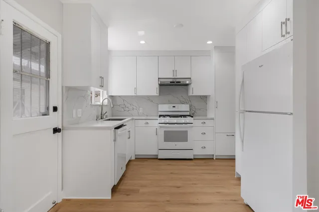 a kitchen with cabinets appliances and a wooden floor
