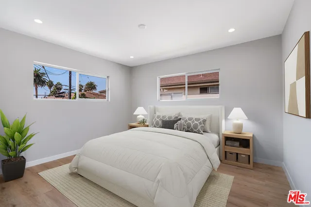 a bedroom with a large bed a potted plant and a window
