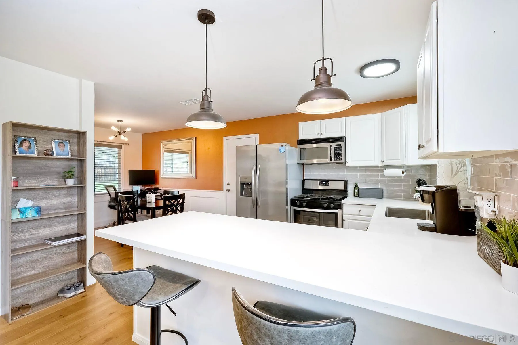 9410 Pike Road Santee, CA 92071 - Photo 9 of 25 a kitchen with stainless steel appliances a stove a sink a oven a dining table and chairs with wooden floor