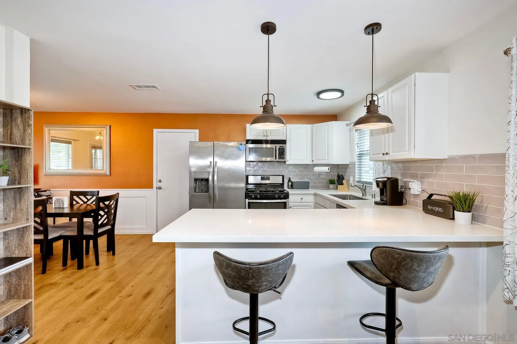 9410 Pike Road Santee, CA 92071 - Photo 10 of 25 a kitchen with stainless steel appliances kitchen island granite countertop a stove a refrigerator a sink a dining table and chairs with wooden floor