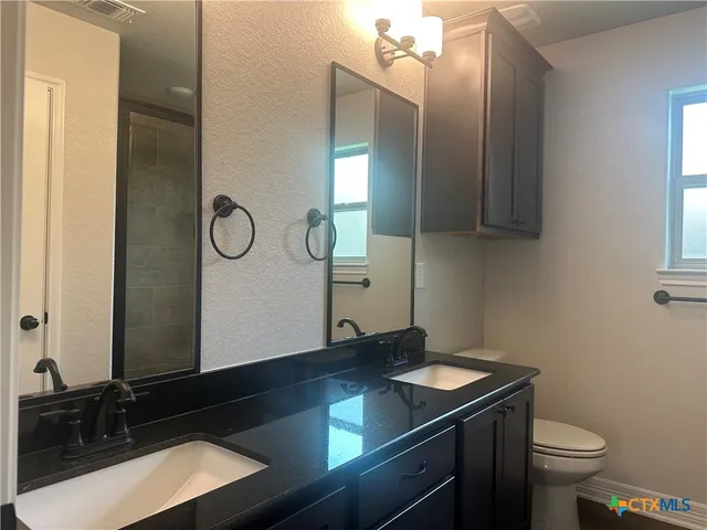 a bathroom with a toilet sink vanity and window