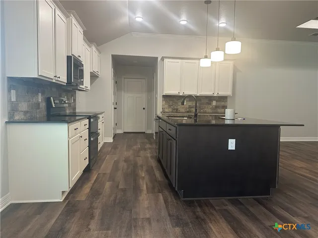 a view of kitchen with kitchen island a sink wooden floor and a refrigerator