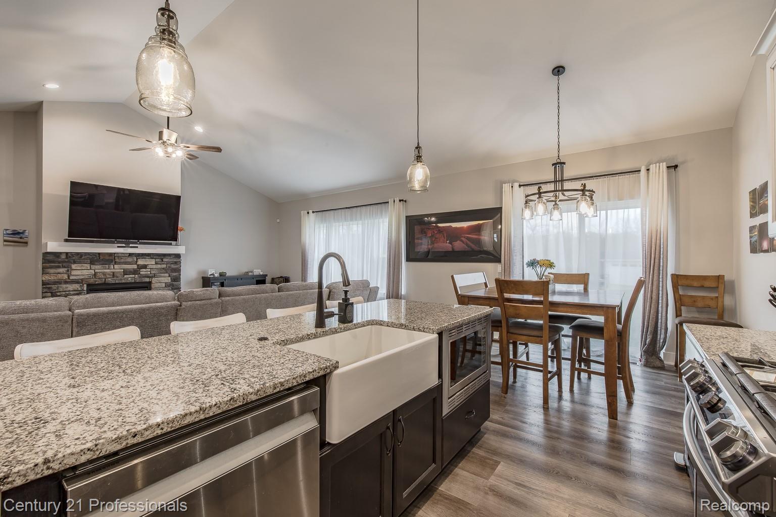 4914 TORATOLA Lane Howell, MI 48843 - Photo 39 of 39 Kitchen with stainless steel appliances, open floor plan, dark wood finished floors, light stone countertops, and a stone fireplace