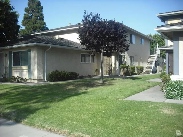 a front view of a house with a yard and palm trees