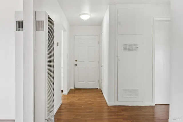 a view of an empty room with wooden floor and a window