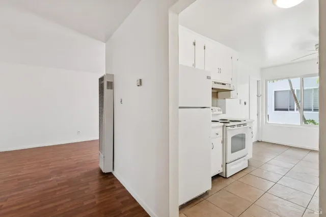 an empty room with a chandelier fan and windows