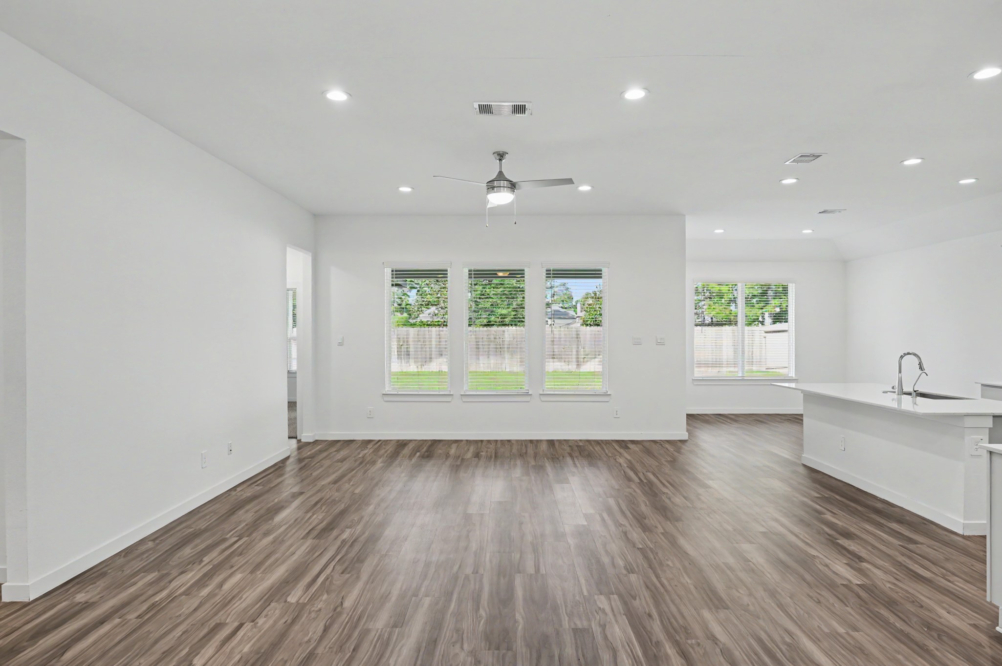 14162 Primrose Ridge Lane Conroe, TX 77384 - Photo 11 of 48 Spacious open-concept living area with elegant wood flooring, abundant natural light from large windows, and a modern kitchen featuring a sleek island and contemporary fixtures.