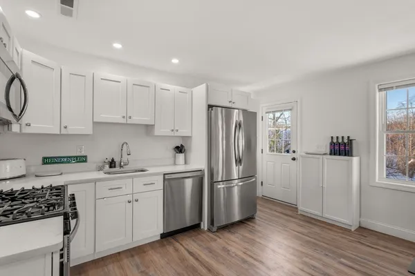 a kitchen with stainless steel appliances kitchen island granite countertop a stove a refrigerator a kitchen island a dining table and chairs with wooden floor