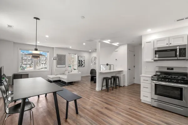 a living room with stainless steel appliances kitchen island granite countertop furniture and a wooden floor
