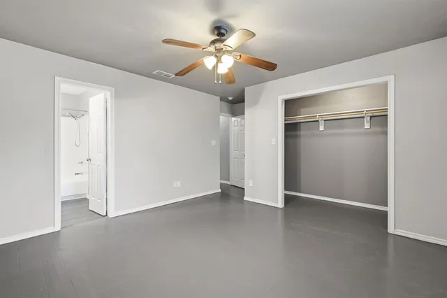 an empty room with closet and a ceiling fan
