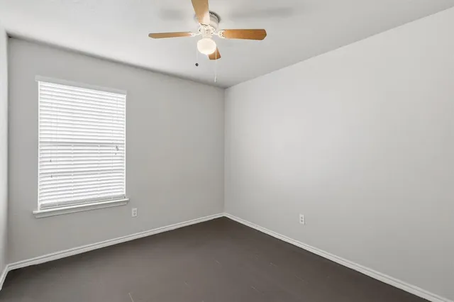 an empty room with a window and a fan