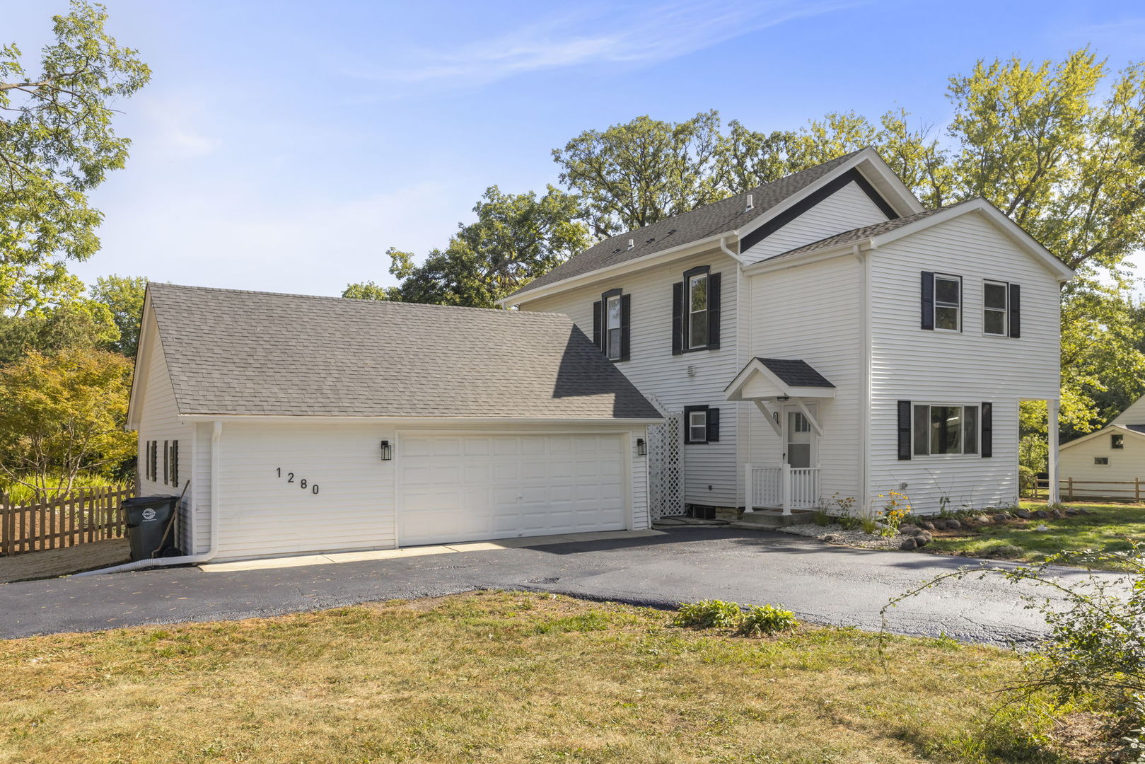 a view of a white house with a yard and large tree