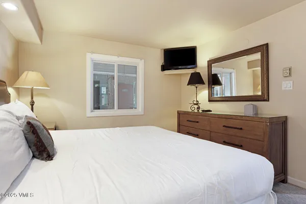 a bedroom with a bed and a flat tv screen on dresser