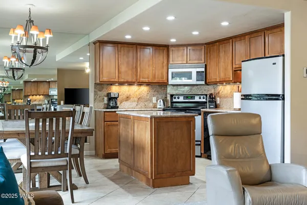 a kitchen with stainless steel appliances granite countertop a refrigerator a stove top oven a sink dishwasher and white cabinets