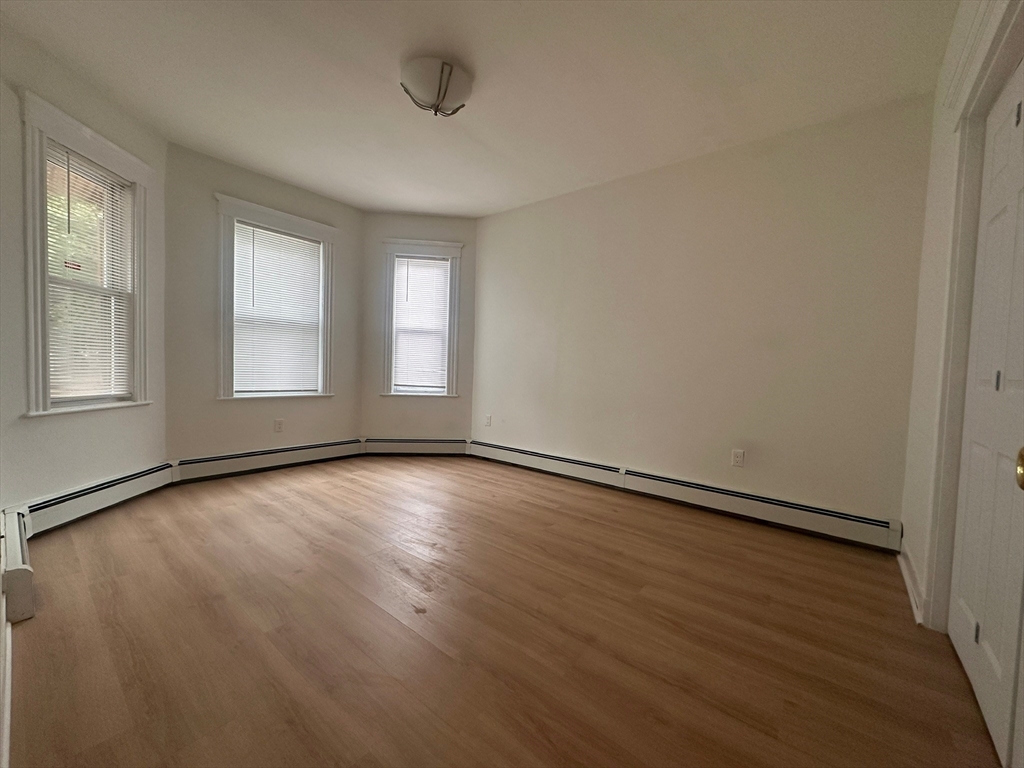 5 Crowell Street, Unit 1 Boston, MA 02124 - Photo 3 of 8 an empty room with wooden floor and windows
