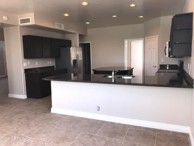 a kitchen with granite countertop a refrigerator and a stove top oven