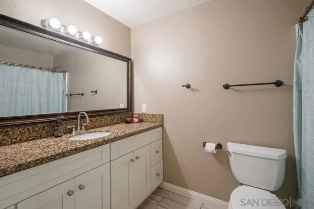 a bathroom with a granite countertop toilet sink and mirror