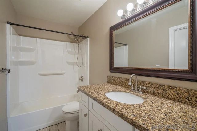 a bathroom with a granite countertop sink toilet and shower