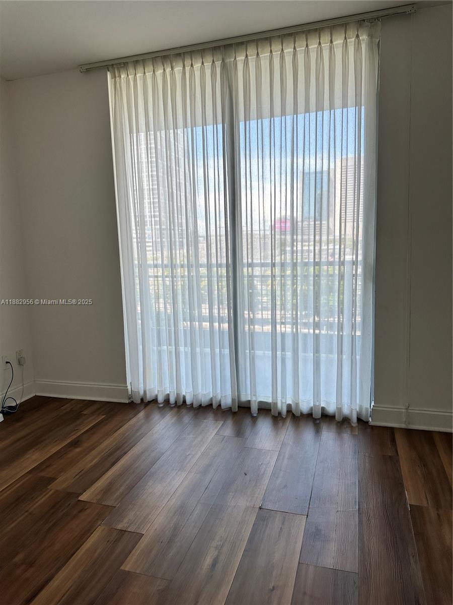 690 Southwest 1st Court, Unit 605 Miami, FL 33130 - Photo 3 of 9 an empty room with wooden floor and windows
