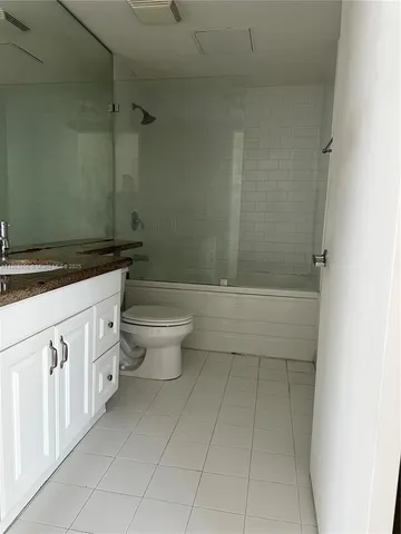 a bathroom with a granite countertop sink a toilet and a shower