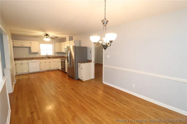 a view of a kitchen with stainless steel appliances wooden floor and a chandelier