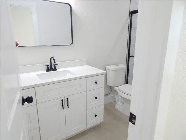 a bathroom with a sink vanity mirror and toilet